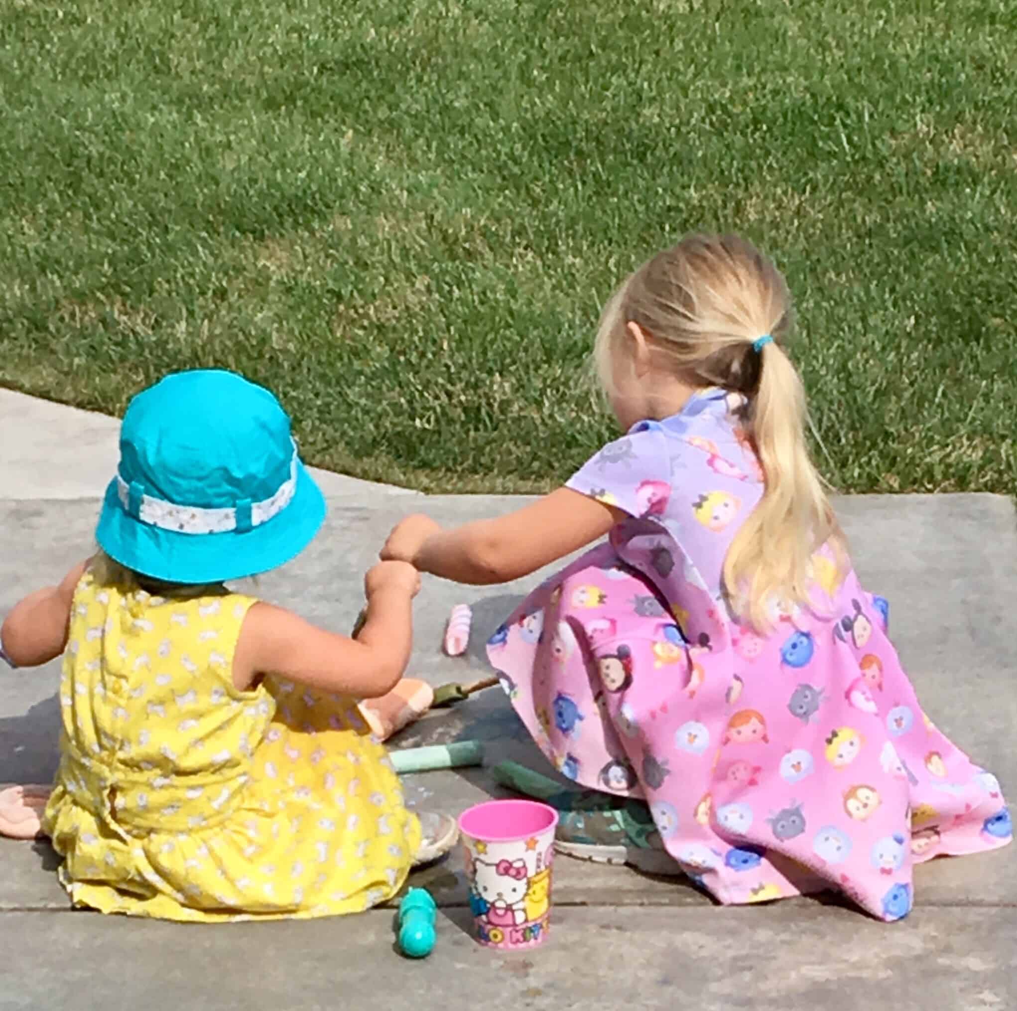 sisters playing with sidewalk chalk