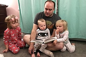 Father reading to and guiding his children