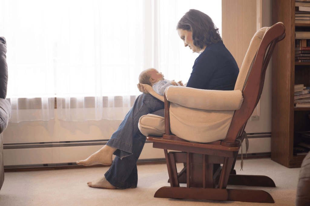 A woman sitting at a table, looking exhausted and overwhelmed, symbolizing mommy burnout