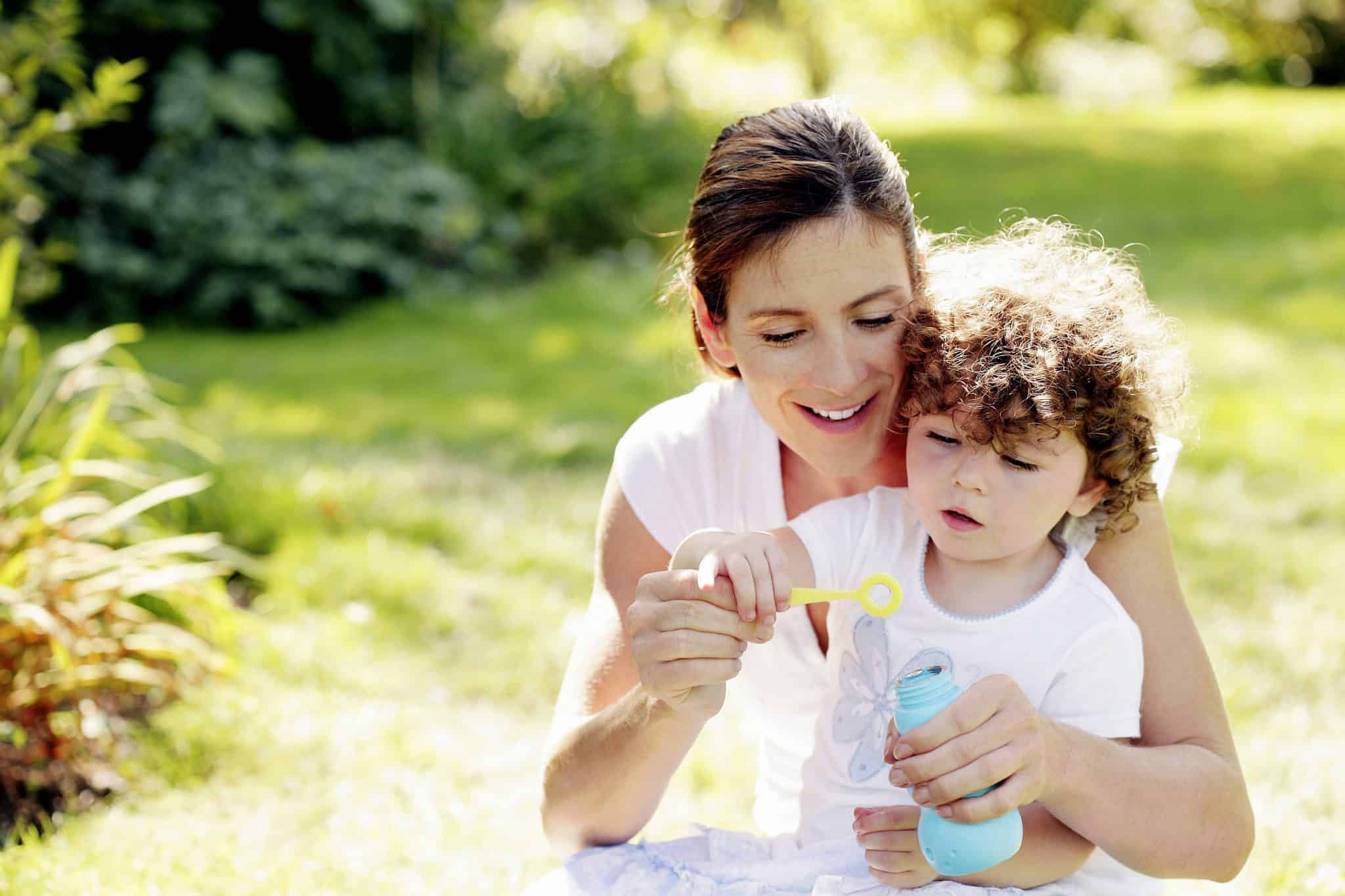 woman blowing bubbles with curly-headed son
