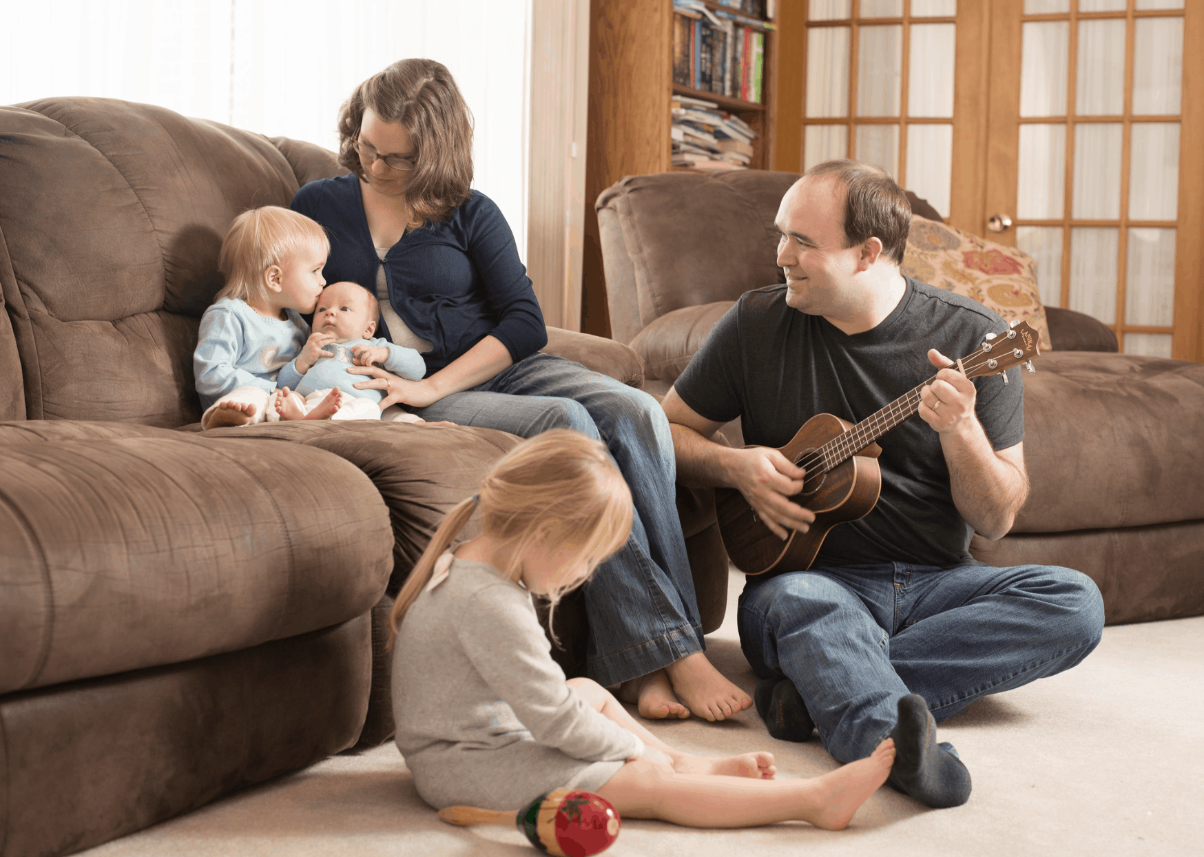 family sitting on couch with preschooler, toddler, and newborn