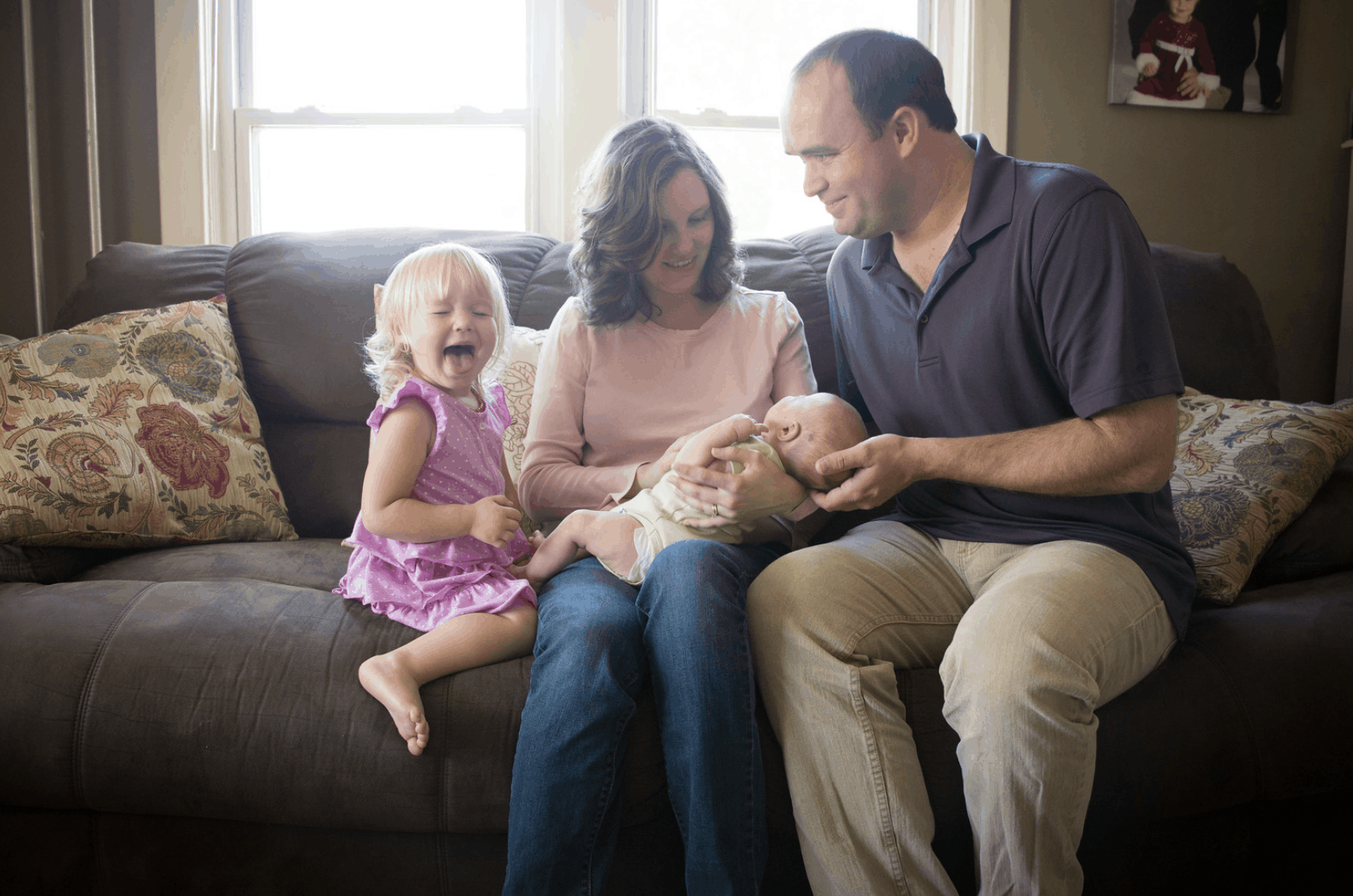 Family sitting on couch with newborn and toddler