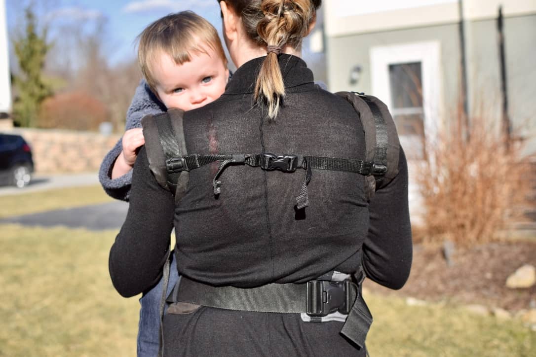 Toddler looking over mother’s back in soft structured carrier