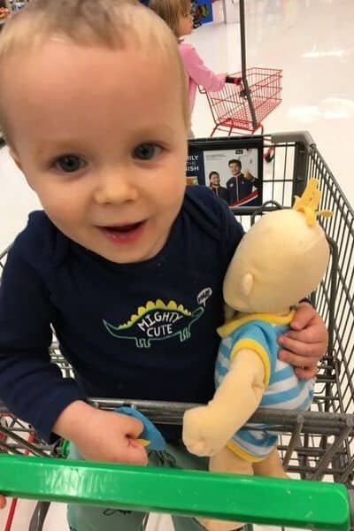 Little boy in shopping cart holding a Baby Stella doll
