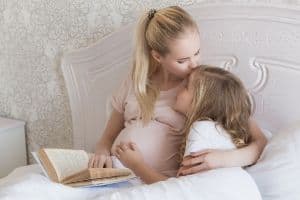 pregnant mother kissing young girl