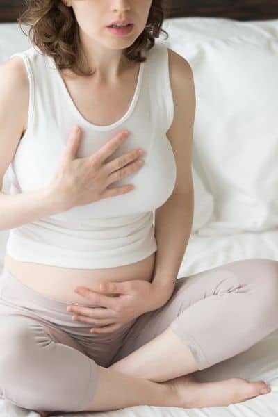Pregnant woman with hands on heart and belly