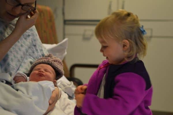 Big sister toddler meeting her newborn baby sister