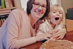 Mother and little girl in front of chocolate cake for weaning party