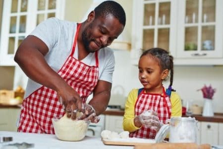 A father and daughter in the kitchen, kneading dough together