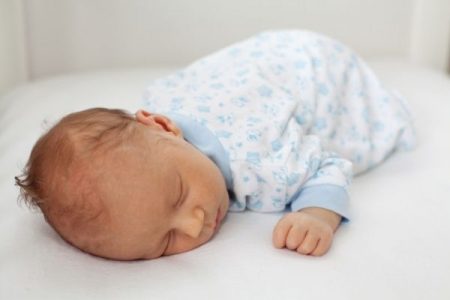 baby in onsie sleeping on non-toxic crib mattress