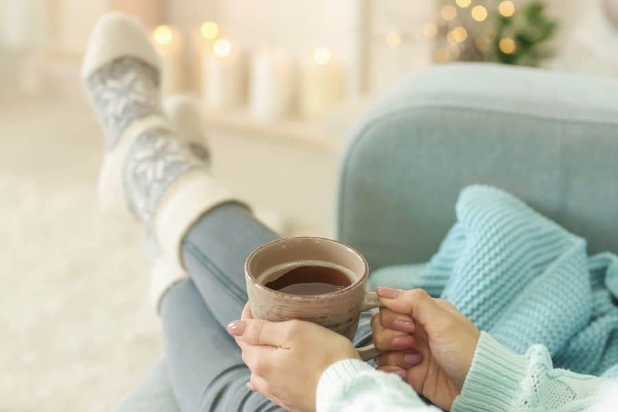 woman sitting in cozy chair with mug of tea