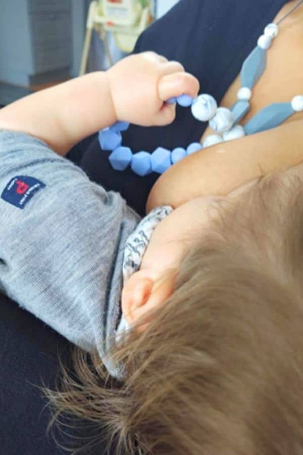 woman wearing nursing necklace while breastfeeding their baby