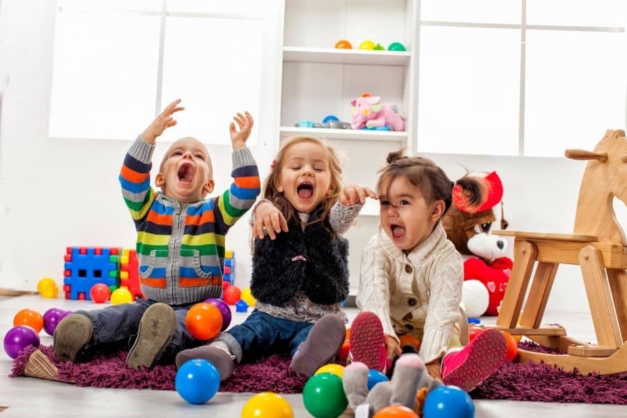 three kids having a blast playing with balls in a play room