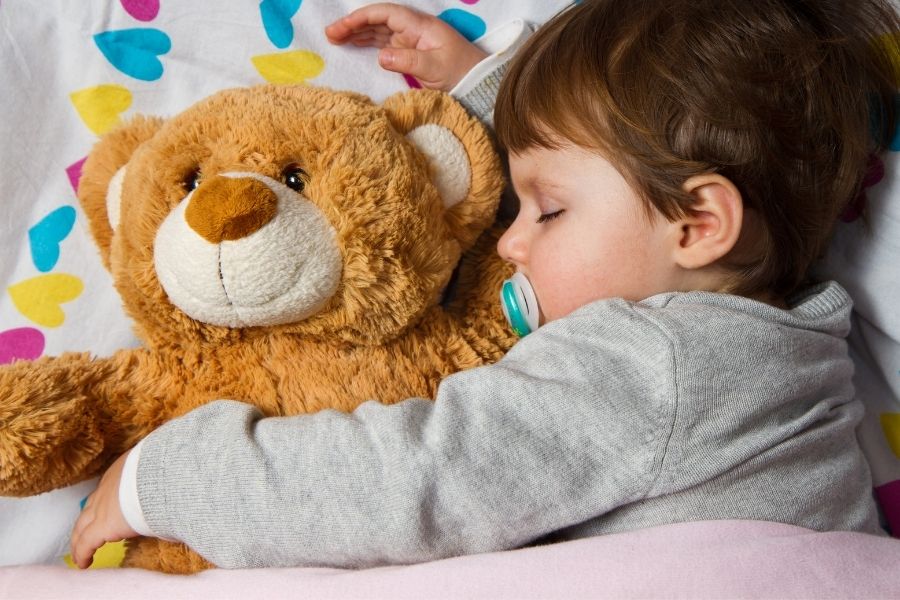 little boy sleeping with teddy bear made of polyester