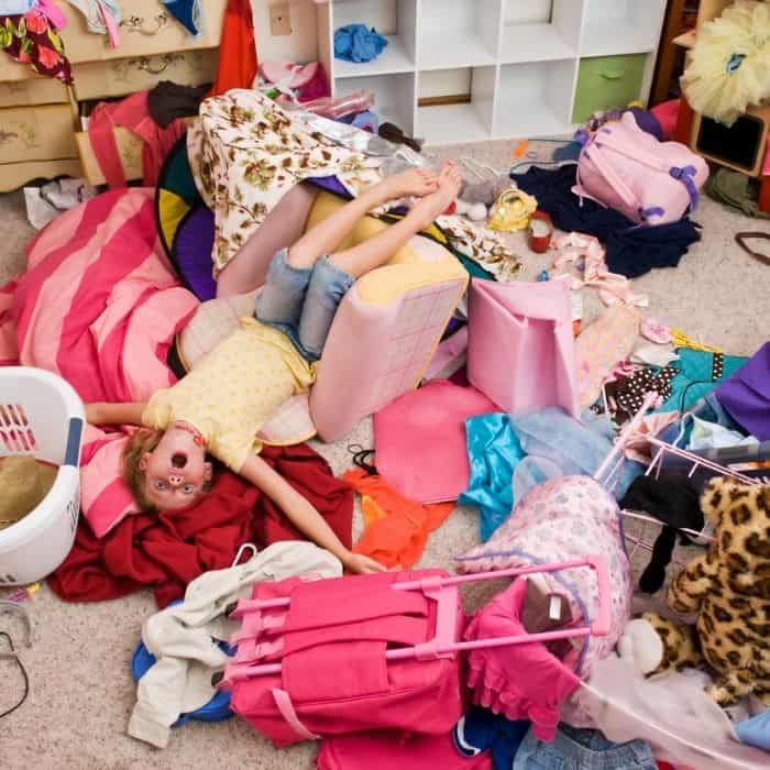 little girl laying in a messy bedroom with toys and clothes everywhere