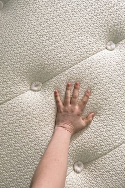 Picture of my hand pressing on the Kiwi mattress's hand tufted surface