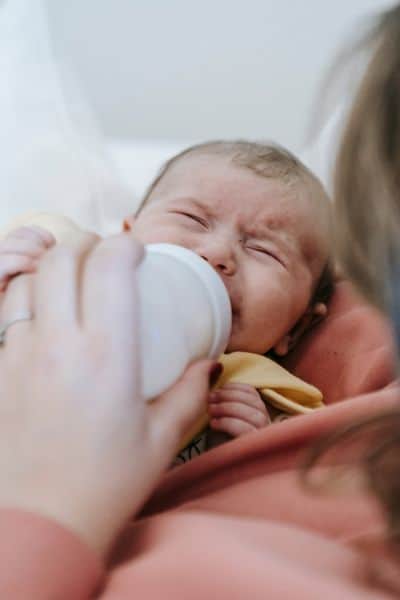 crying baby with slightly clenched fists, too upset to eat from bottle