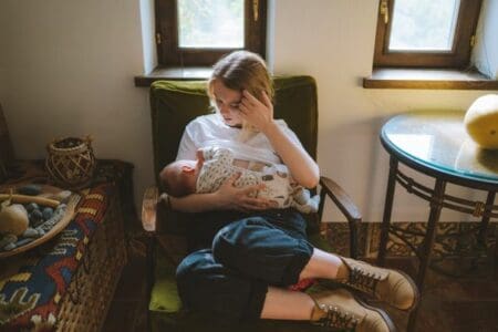 A mother breastfeeding her baby while sitting in a sofa