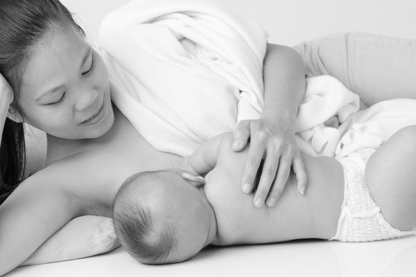 mother lying on side with baby and breastfeeding