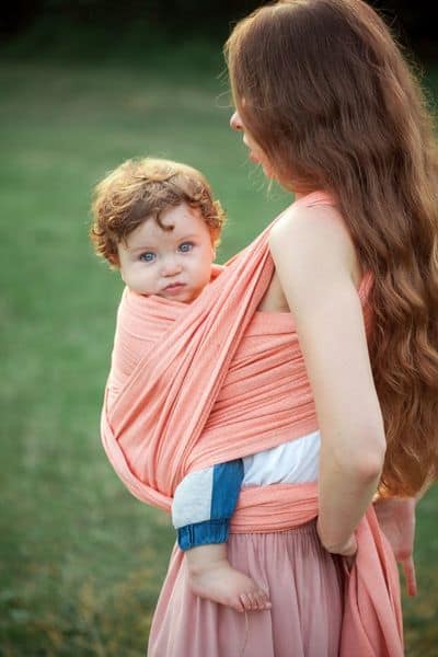 Infant in stretchy wrap being held by mother