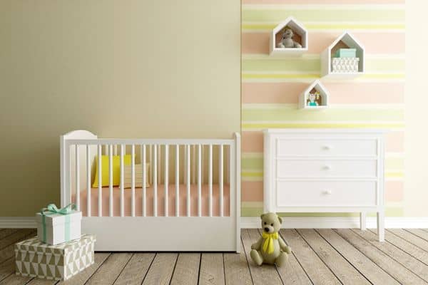 White non toxic nursery furniture, including an eco friendly crib and a green baby dresser in a room with soft yellow and pink decor.