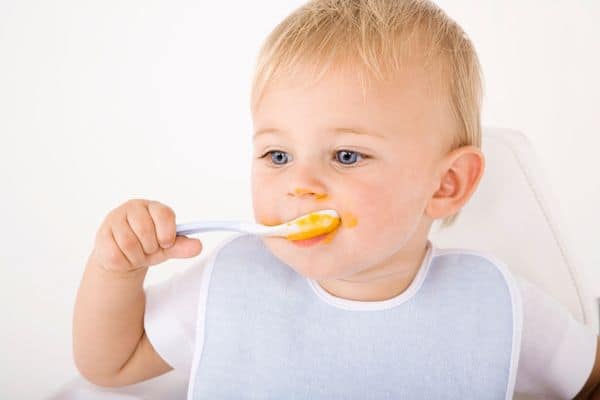 one year old breastfeeding baby eating solid food