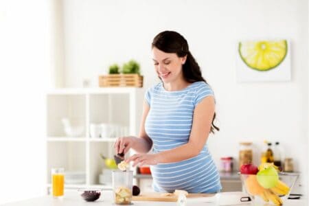 Pregnant woman making a smoothie in a blender